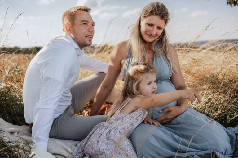Familie bei Babybauchshooting im Sommer in der Natur bei Dresden mit großer Schwester